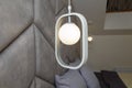 Modern lit, white lamp, illuminator with geometry oval decorative element, soft fabric head of bed, bedroom interior design