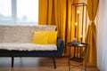 Modern living room with black coffee table, yellow pillows on dark blue coach and yellow courtains.