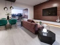 Modern living room combined with dining room. Wall mounted tv unit stand on a wooden wall made of planks. Green, burgundy, brown,