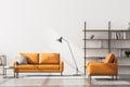 Modern living room interior, white wall. Yellow 2 sitter sofa with stripe cushion and one armchair, coffee table, bookshelves and