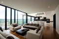 Modern living room with large windows, comfortable sofas, an open-plan kitchen, featuring sleek designs and a scenic view Royalty Free Stock Photo