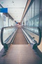 Modern long walkway of escalator moving forward at airport terminal.