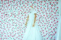 Modern long white wedding dress on a mannequin with blured pink flower background