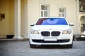 Modern luxury BMW 750Li XDrive car front view parked on stone paved parking near ancient house horizontal