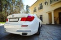 Modern luxury BMW 750Li XDrive car rear back close-up view parked on stone paved parking near ancient house with balconies with Royalty Free Stock Photo