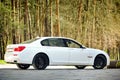 Modern luxury BMW 750Li XDrive car three-quarter side view parked on stone paved parking near ancient house