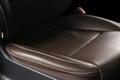 Modern luxury car brown leather interior. Part of leather car seat details with white stitching. Interior of prestige car. Comfort