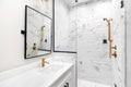 A modern, luxury white bathroom with gold hardware.