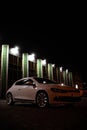 Modern luxury white sedan 2-doors sport car is parked at the night parking at the city neat the shopping center. Royalty Free Stock Photo