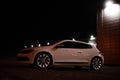 Modern luxury white sedan 2-doors sport car is parked at the night parking at the city neat the shopping center. Royalty Free Stock Photo