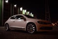 Modern luxury white sedan 2-doors sport car is parked at the night parking at the city neat the shopping center. Royalty Free Stock Photo