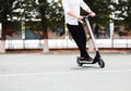 Modern man in stylish black and white outfit riding electric scooter in the city