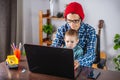 Modern man is working on a laptop, and his little son is sitting on his lap. Concept of family and remote work from home Royalty Free Stock Photo