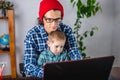 Modern man is working on a laptop, and his little son is sitting on his lap. Concept of family and remote work from home Royalty Free Stock Photo