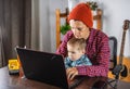 Modern man is working on a laptop, and his little son is sitting on his lap. Concept of family and remote work from home Royalty Free Stock Photo