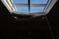 Modern mansard window with blinds in an attic room against blue sky