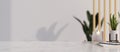 Modern marble white tabletop with candle, plant, stuff and copy spaceover the white wall