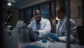 Modern Medical Research Laboratory: Caucasian and Black Scientists Work on Laptop, Do Data Analysi