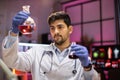 Indian male scientist working with flask, analysing biochemicals samples.