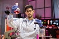 Indian male scientist working with flask, analysing biochemicals samples.