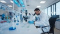 Modern Medical Research Laboratory: Male Scientist Working with Microscope, Analysing Biochemicals