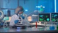 Modern medical research laboratory. Woman researcher in a white gown, mask, blue gloves and a bonnet is examining a