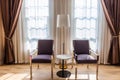 Modern metal chairs and marble tables in a room with windows and curtains