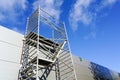 Modern metal scaffolding next to a new building gray sandwich panel wall, blue sky background Royalty Free Stock Photo