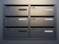 Modern metallic mailboxes with numbered compartments arranged in a grid against a grey wall Royalty Free Stock Photo