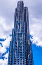 Modern metallic shiny skyscraper with wavy shape facade and cloudy blue sky