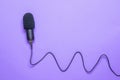 Modern microphone with a long cord on a purple background