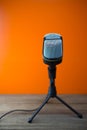 Modern microphone with orange background and wooden floor, soft