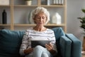 Modern mature woman relax on couch using tablet