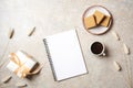 Modern minimal home workspace desk with blank paper notebook, coffee cup, waffles, dry flowers, gift box on concrete stone Royalty Free Stock Photo