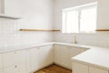 Modern minimal kitchen design. Stylish white kitchen cabinets with brass knobs, faucet, granite island and wooden shelves in new Royalty Free Stock Photo