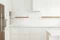 Modern minimal kitchen design. Stylish white kitchen cabinets with brass knobs, wooden shelves and appliances in new scandinavian Royalty Free Stock Photo