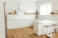 Modern minimal kitchen design. Stylish white kitchen cabinets with brass knobs, wooden shelves with utensils and appliances in new Royalty Free Stock Photo