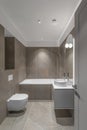 Modern minimalist bathroom beige interior design with marble tiles and beige furniture.