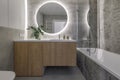 Modern minimalist bathroom interior design with wooden furniture, grey stone tiles, round mirror. Royalty Free Stock Photo