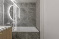 Modern minimalist bathroom interior design with wooden furniture, grey stone tiles, round mirror. Royalty Free Stock Photo