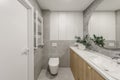 Modern minimalist bathroom interior design with wooden furniture, grey stone tiles, round mirror.