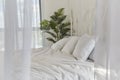 Modern minimalist bedroom with white linens and indoor palm plant Royalty Free Stock Photo