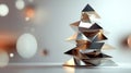 Modern and minimalist christmas tree sculpture made of gold and silver triangles, standing on a white surface with a Royalty Free Stock Photo