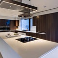 2 A modern, minimalist kitchen with a mix of white and natural wood cabinetry, a large waterfall countertop, and a sleek range h Royalty Free Stock Photo