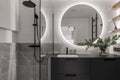 Modern minimalistic bathroom interior design with grey stone tiles, black furniture, eucalyptus in glass vase Royalty Free Stock Photo