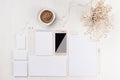 Modern minimalistic elegant feminine work space with white blank stationery, coffee, flowers, phone on white wood board.