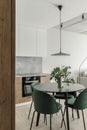 Modern minimalistic kitchen and dining room interior with wooden and white surfaces, green chairs and eucalyptus in ceramic vase. Royalty Free Stock Photo