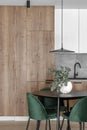 Modern minimalistic kitchen and dining room interior with wooden and white surfaces, green chairs and eucalyptus in ceramic vase. Royalty Free Stock Photo