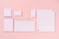 Modern minimalistic workspace with white blank stationery on soft pastel pink background, top view.