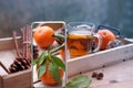 Modern mobile phone with screen, glass of hot tea on tray, delicious vitamin tangerines with leaves, cinnamon sticks, pine cones,
